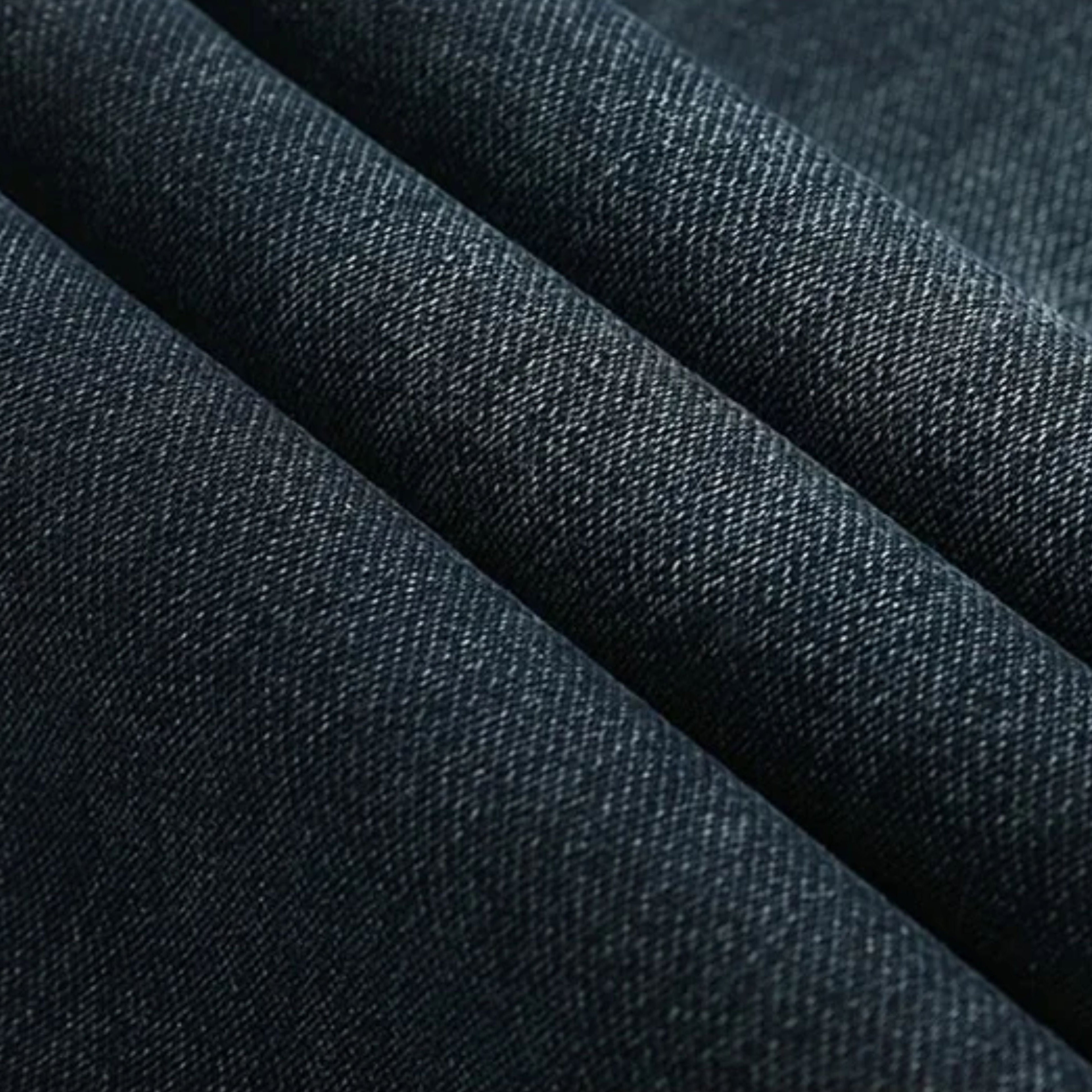 Macro shot of the dark blue denim folded over itself, demonstrating the flexible softness and clean grain of the softener-finished tatting weave