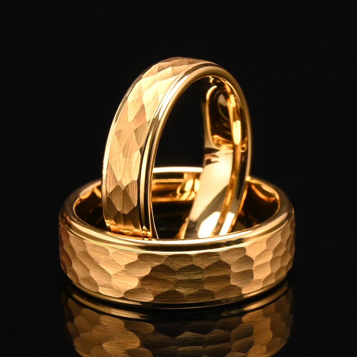 Two 24k gold-plated hammered tungsten rings arranged together on a reflective dark surface to illustrate a matching couples wedding set
