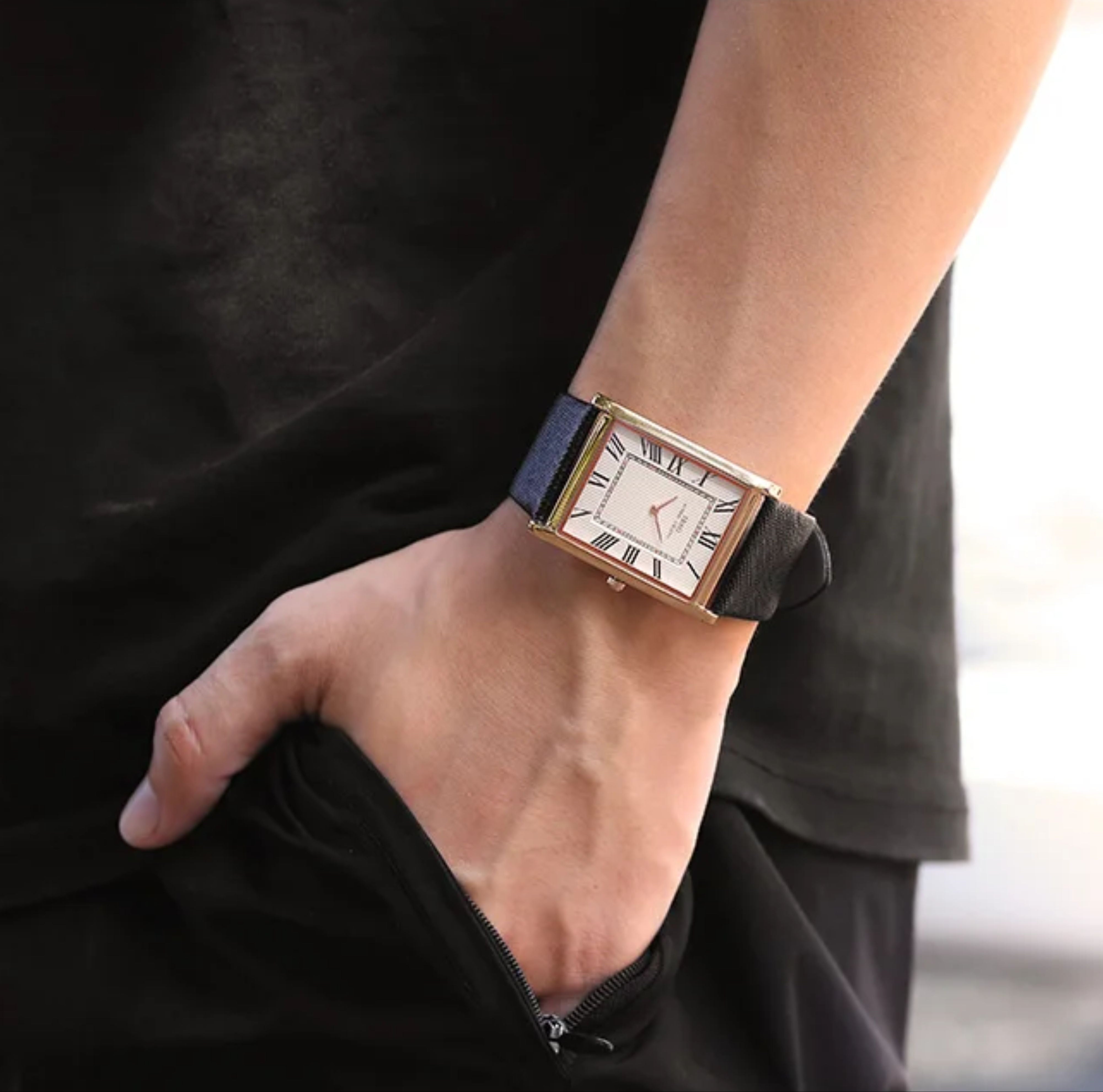 A male model wearing a black shirt standing with his hand in his pocket, showcasing the rose gold IBSO rectangle watch with a white Roman numeral dial