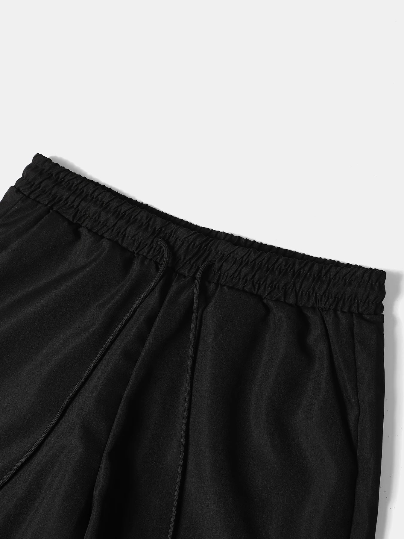 Macro close-up shot of the casual black summer shorts, showcasing the gathered elastic waistband design and integrated front drawstring closure