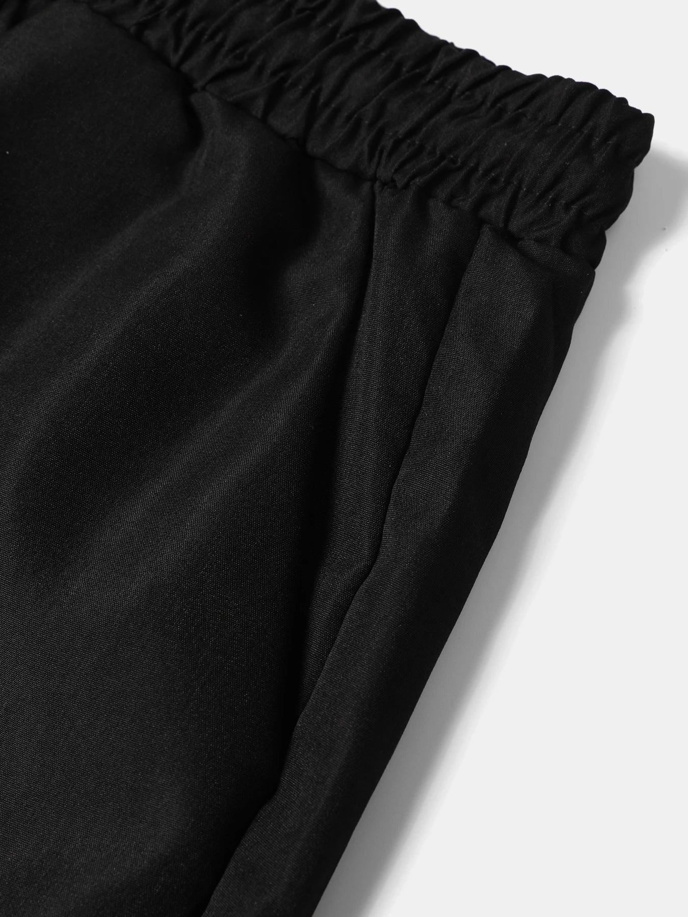Close-up view of the black thin polyester drawstring pants, highlighting the neat side seam pocket construction and lightweight fabric texture