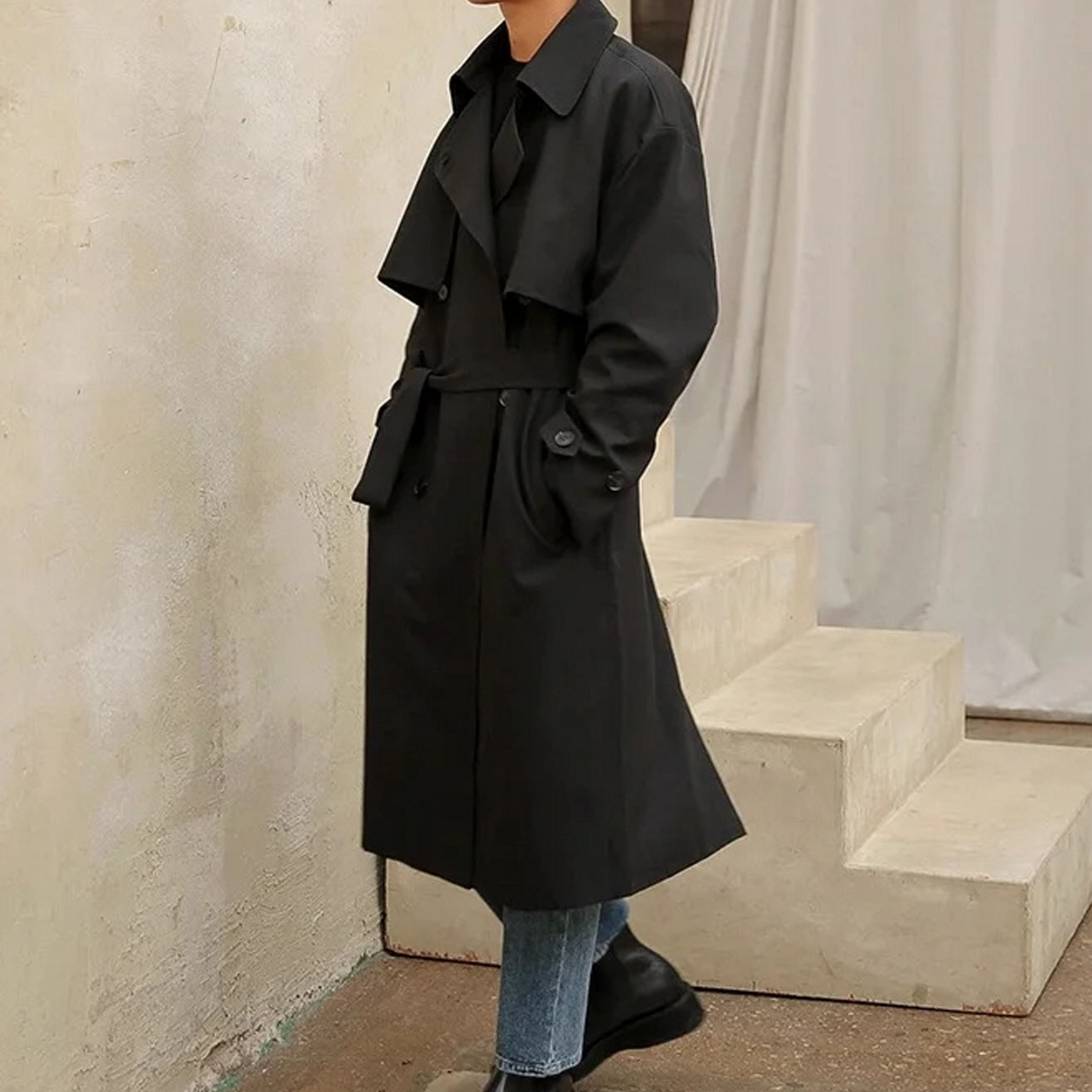 Fashion lookbook of man wearing refined silhouette black long coat with leather boots