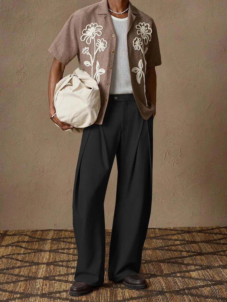 Full body shot of a model wearing elegant black pleated suit pants for men with an open shirt