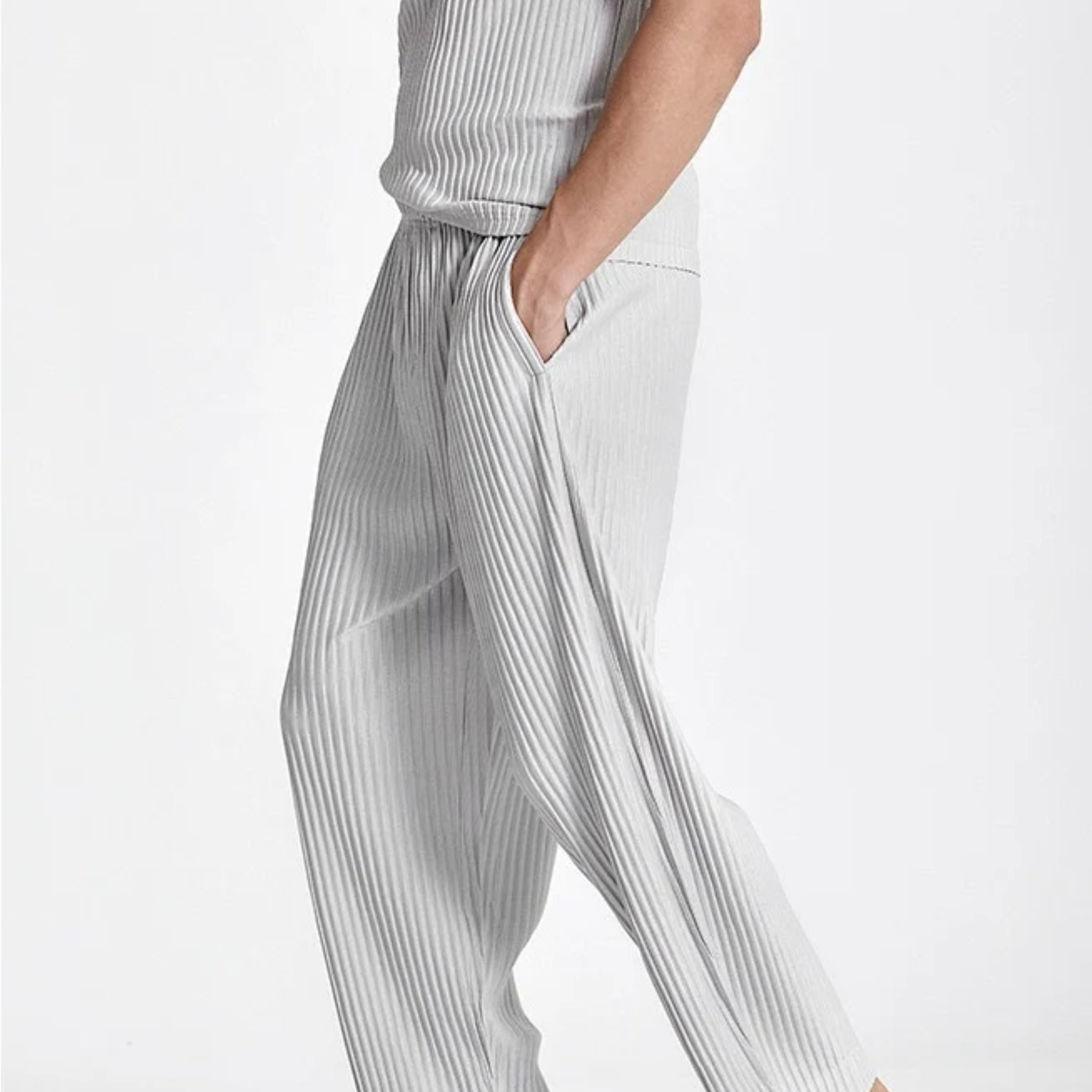 Close-up side view of a man styling the grey ice silk pleated trousers with his hand in the pocket