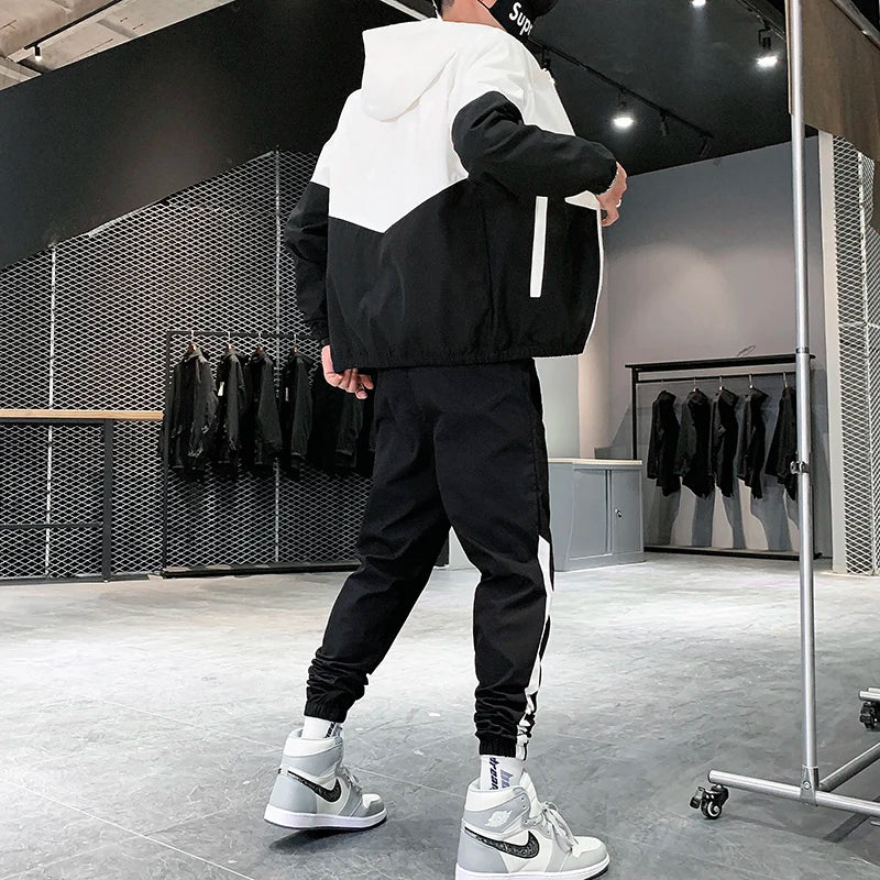 Rear view of a male model wearing the black and white hooded tracksuit jacket and nine-cents joggers with high-top basketball sneakers