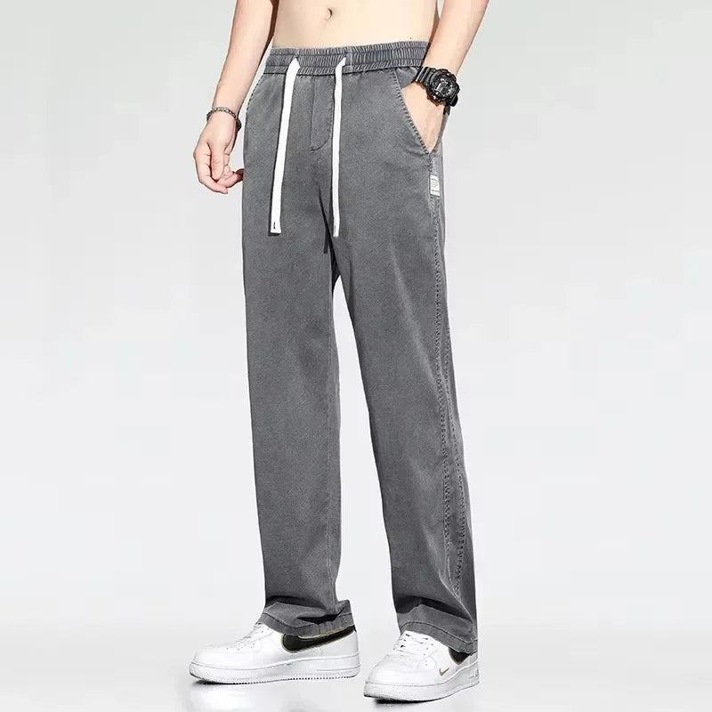 Front view of a model styling medium gray lightweight casual Lyocell pants with an adjustable waist tie