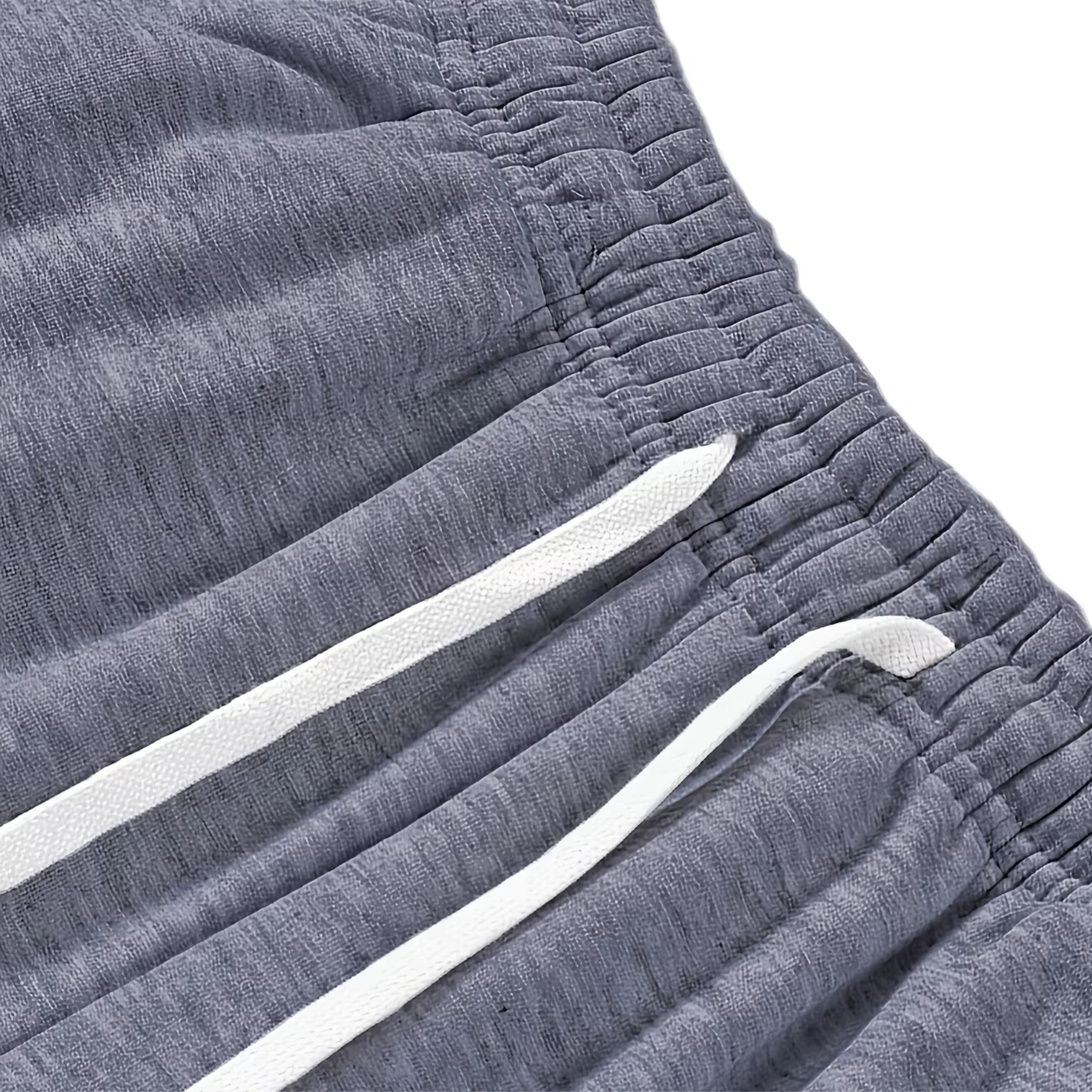 Macro view of the gathered elastic waistband and white drawstrings on a dark grey knitted cotton-feel polyester jogger pants fabric