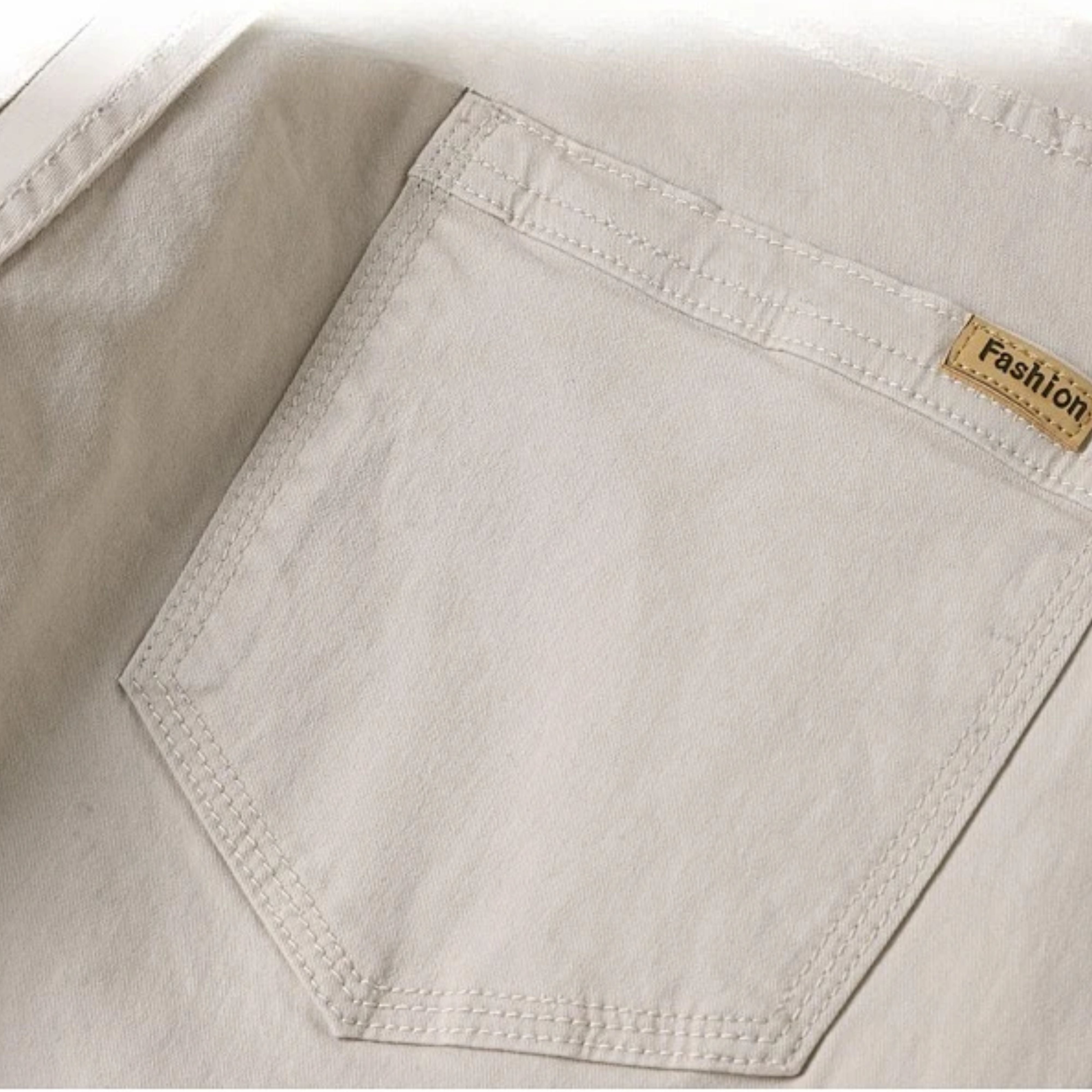 Macro view of the traditional clean back pocket stitching on the off-white ivory jeans, highlighting the high-precision tatting weave texture
