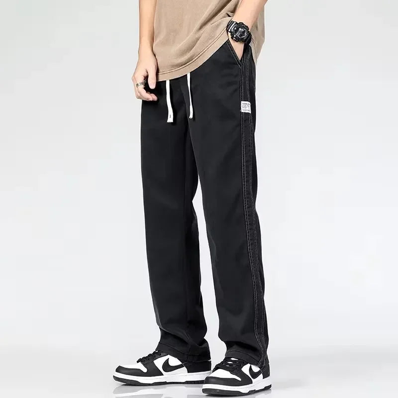 Model wearing black loose straight-leg summer trousers with an elastic drawstring waist and black-and-white sneakers