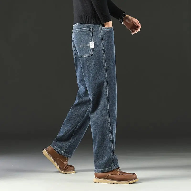 Side profile view of a male model walking, showcasing the spacious wide-leg drape and pocket decoration of the medium blue stretch jeans