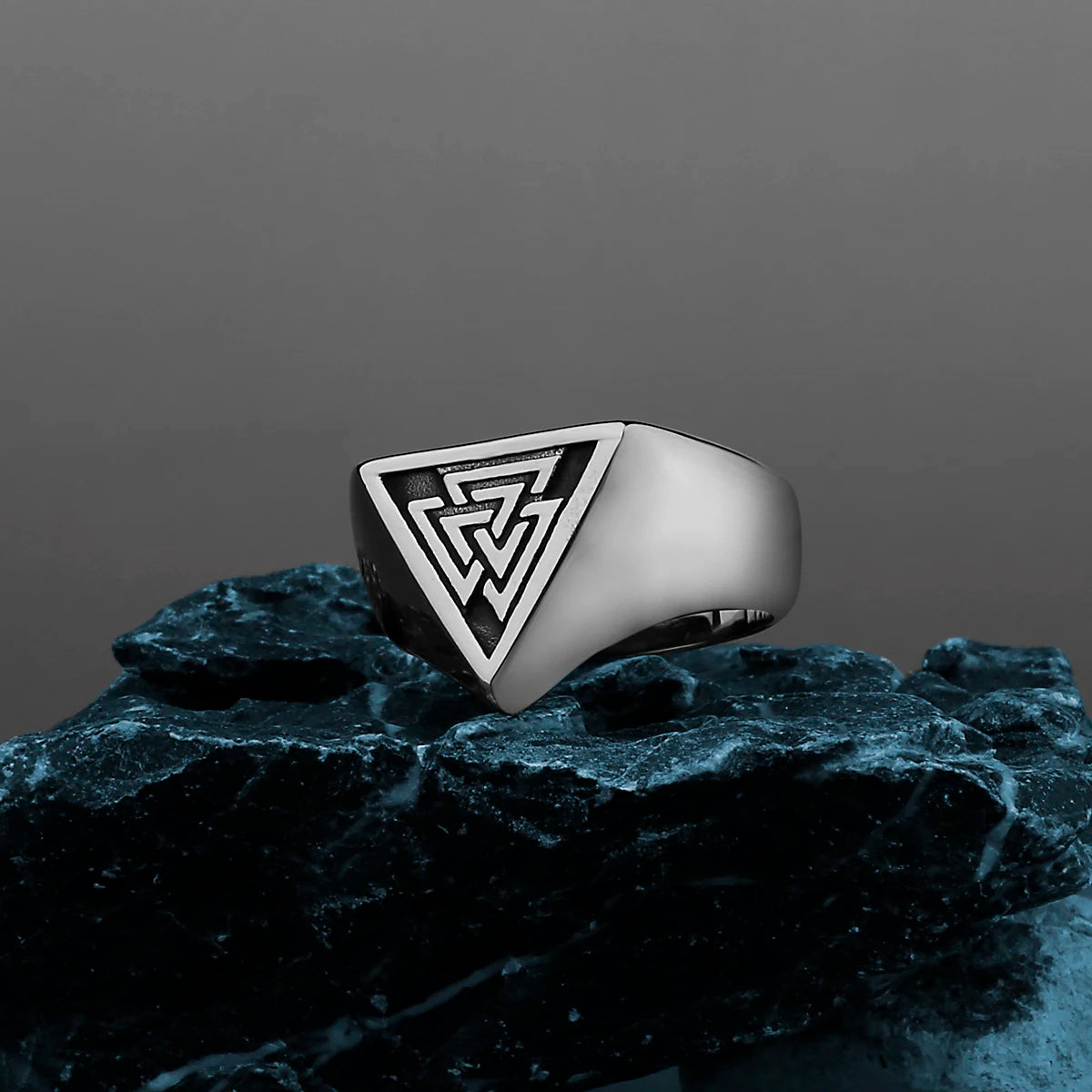 Sterling silver Norse mythology ring with interlocking triangles design resting on dark tree bark.