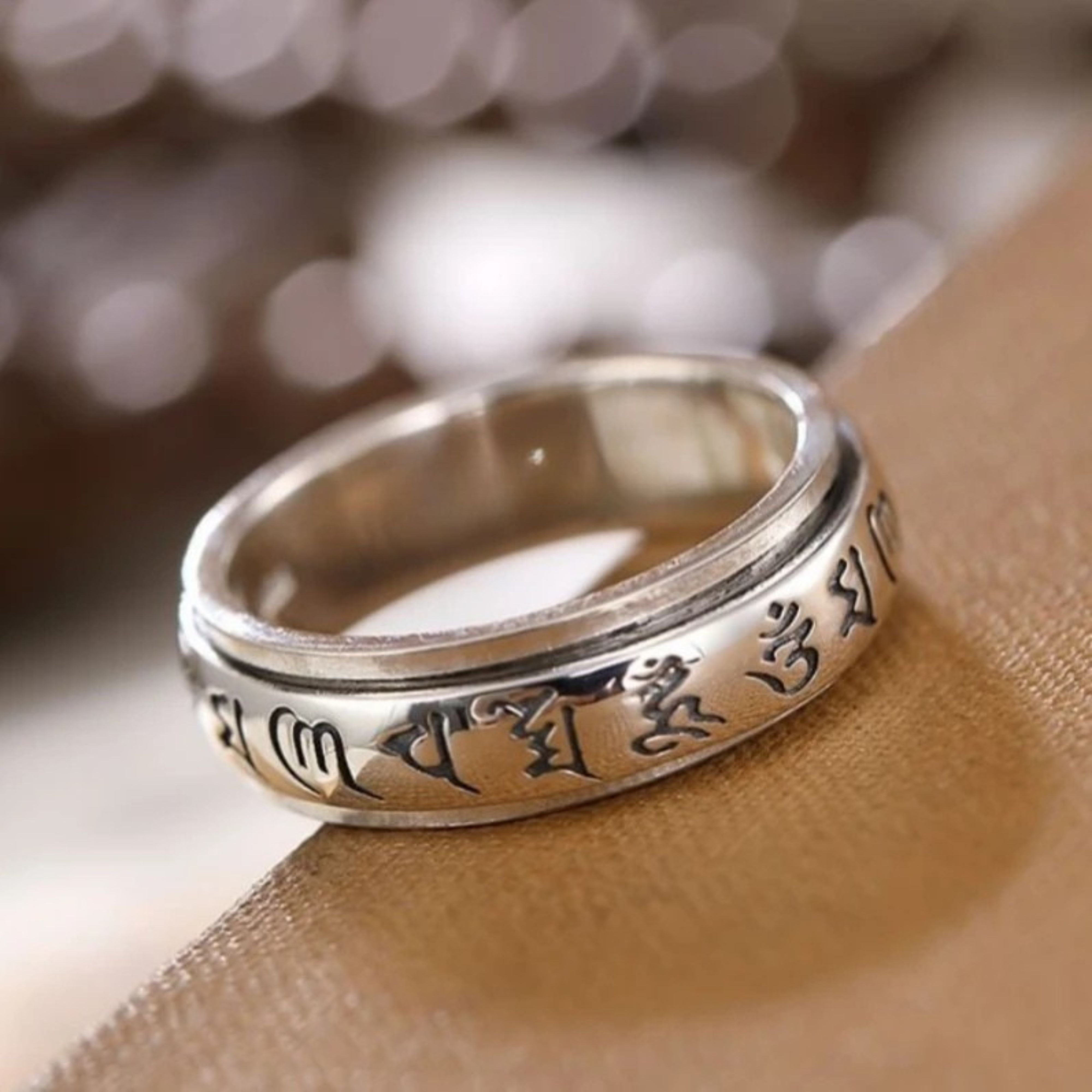 Macro shot of a vintage silver Tibetan prayer ring highlighting the deep, clear engraving of the six-character mantra.