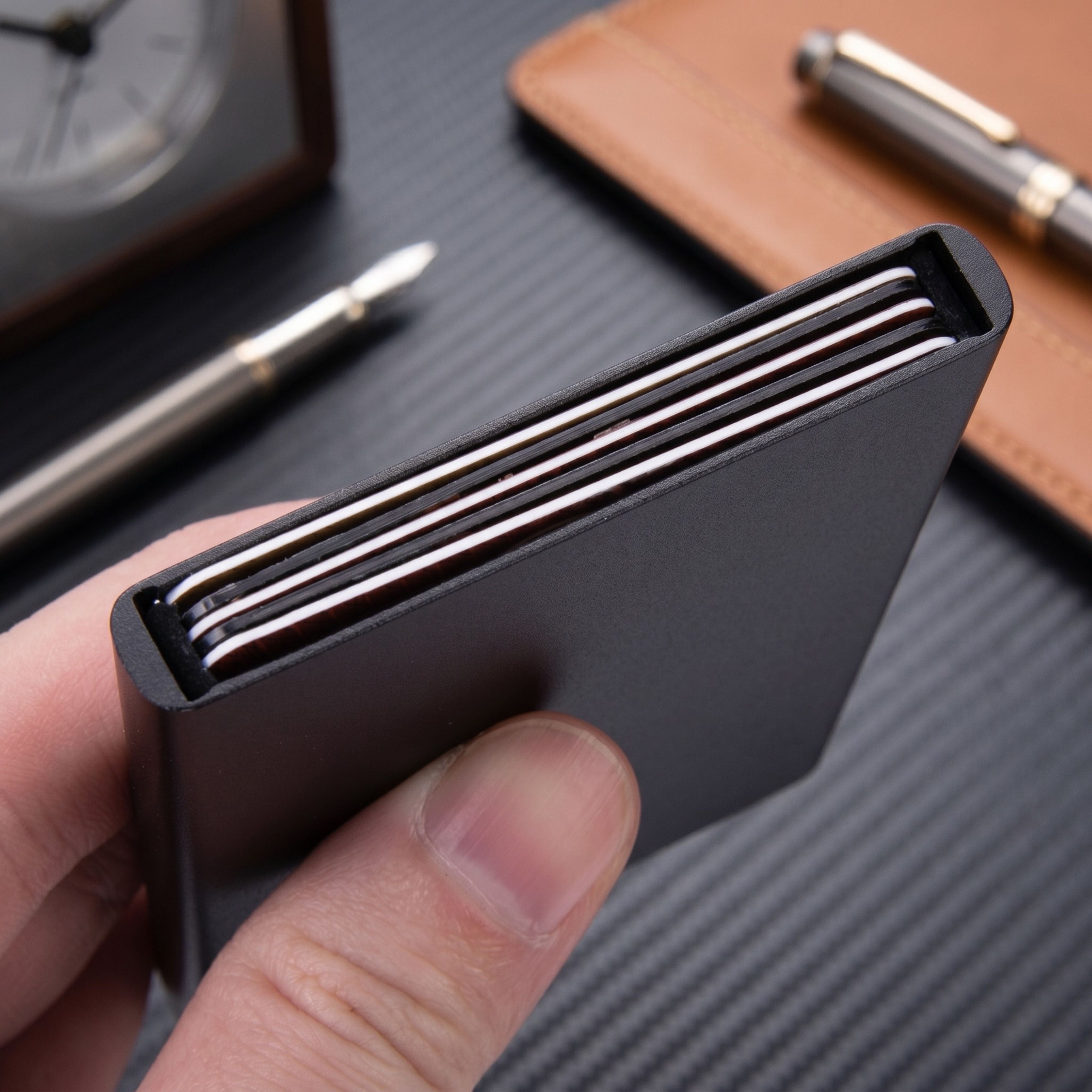 Profile angle shot of a hand holding the ZeAiLi minimalist metal wallet, emphasizing the mechanical slider lever trigger at the base