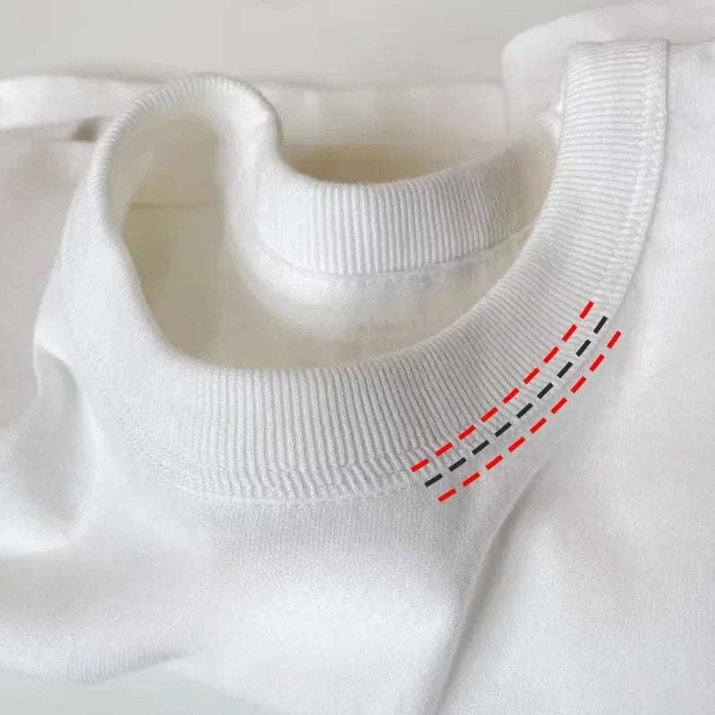 Close-up studio macro shot of a white heavy cotton t-shirt collar, highlighting the clean, parallel red contrast reinforcement stitching