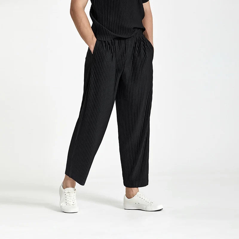 Three-quarter front view of a model showcasing the regular fit and elastic waist comfort of the black pleated pants