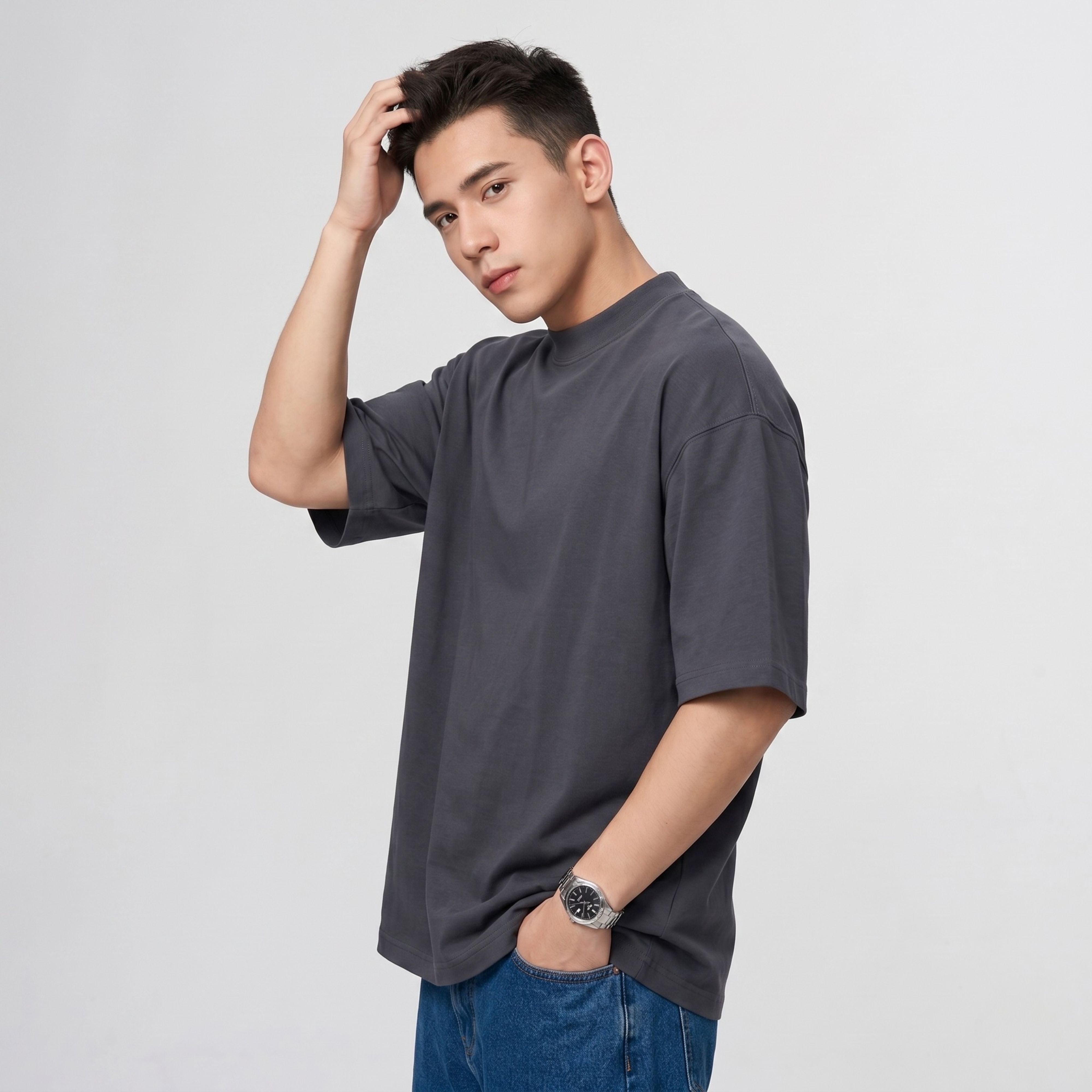 Side angle view of a male model wearing the blank charcoal grey 425g streetwear t-shirt against a clean white background