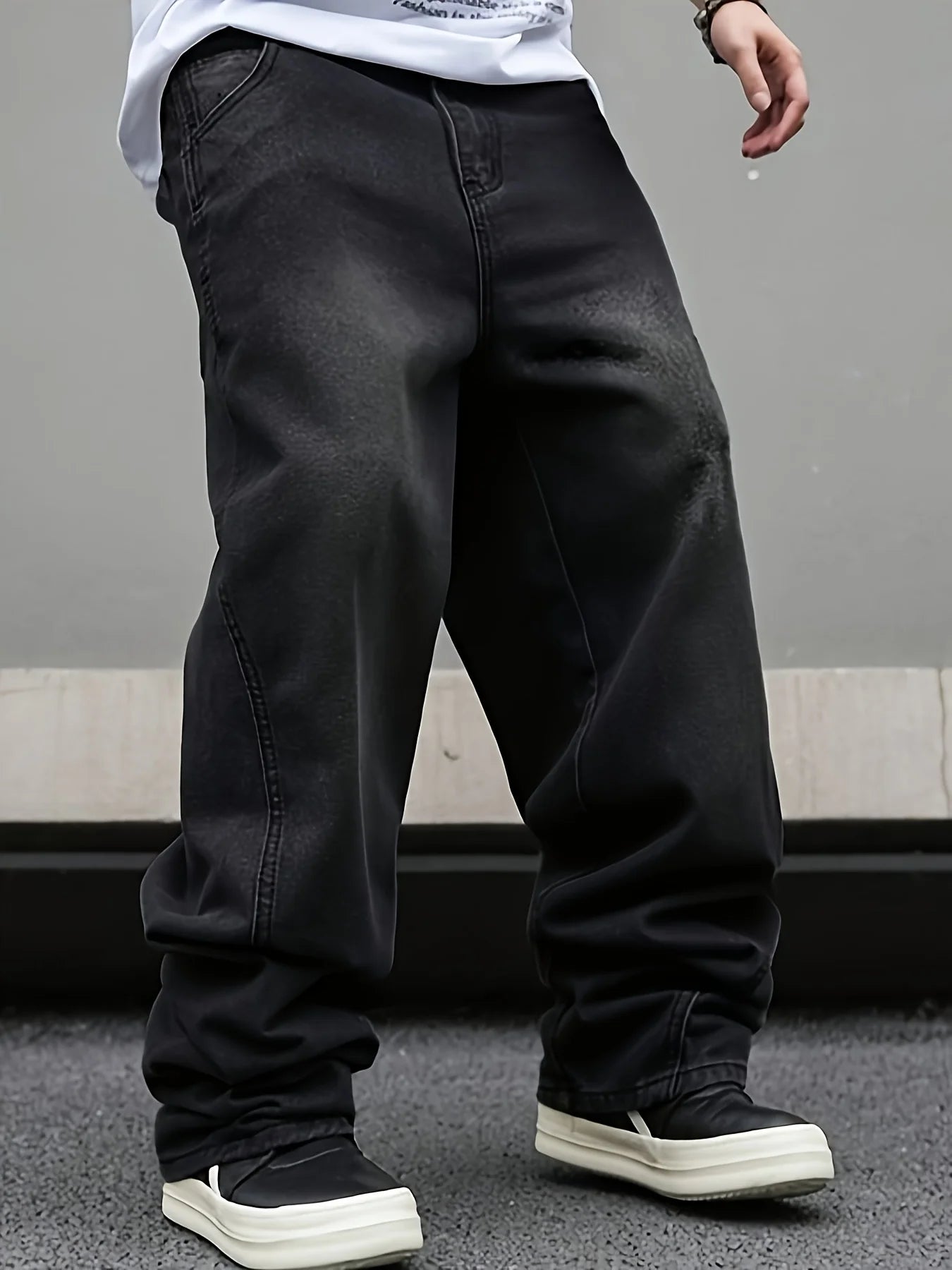 Side shot of a man wearing modern micro flared loose jeans in washed black denim for an American vibe streetwear look