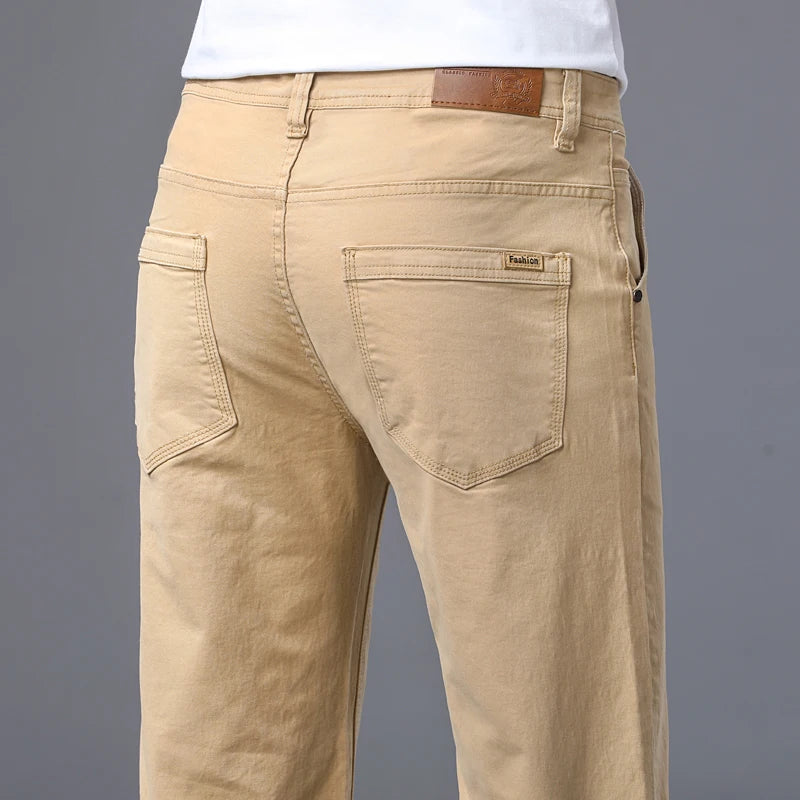 Side walking profile of a male model wearing the sand beige slim straight stretch jeans paired with white minimalist leather sneakers