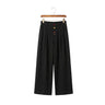 Front view of men's wide-leg pleated trousers in black featuring distinct colorful buttons on a wooden hanger