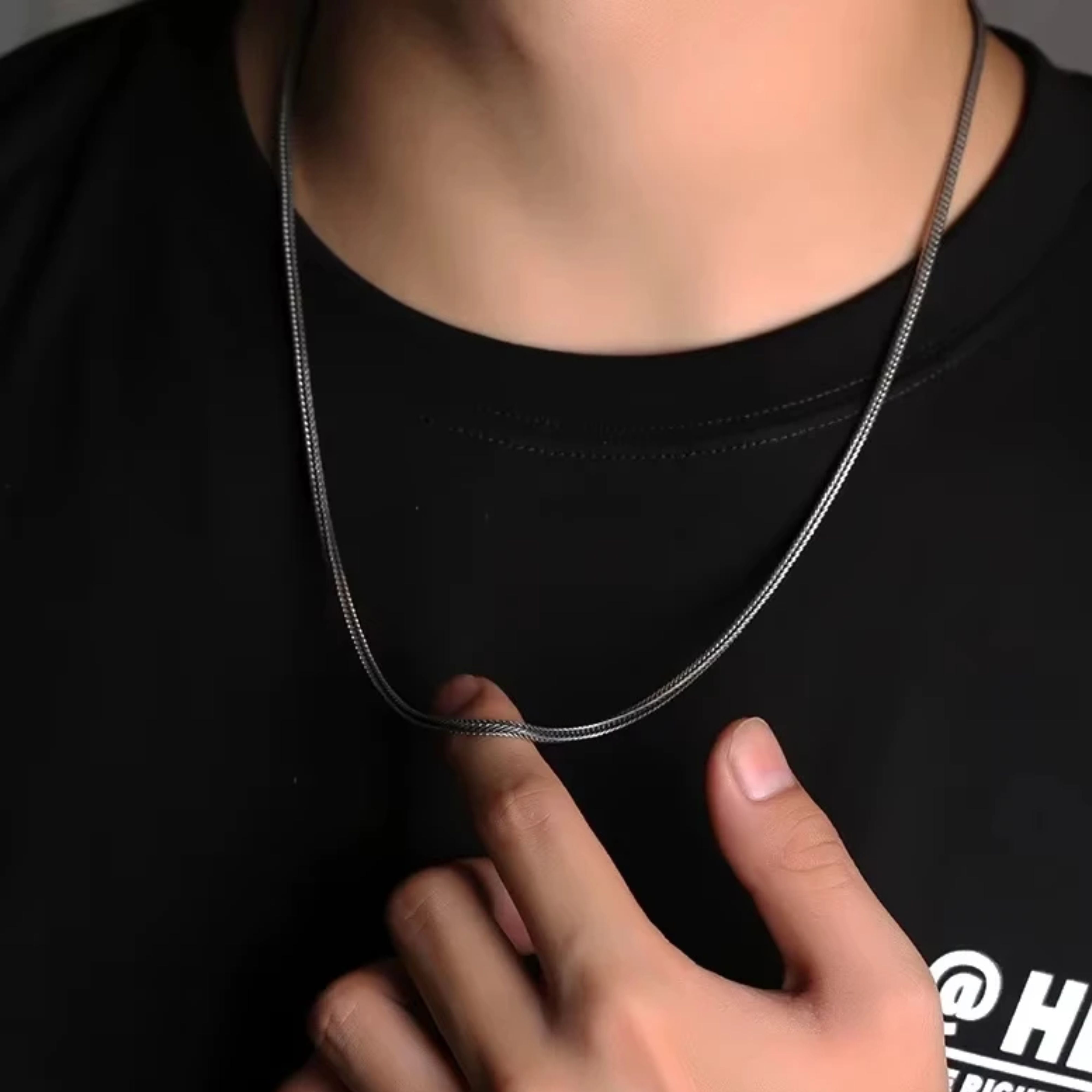 Model wearing a men's oxidized silver woven foxtail chain necklace over a casual black t-shirt.