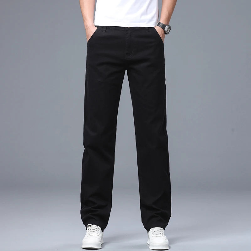 Front crop view of a model wearing the solid black slim straight stretch denim pants with clean white sneakers
