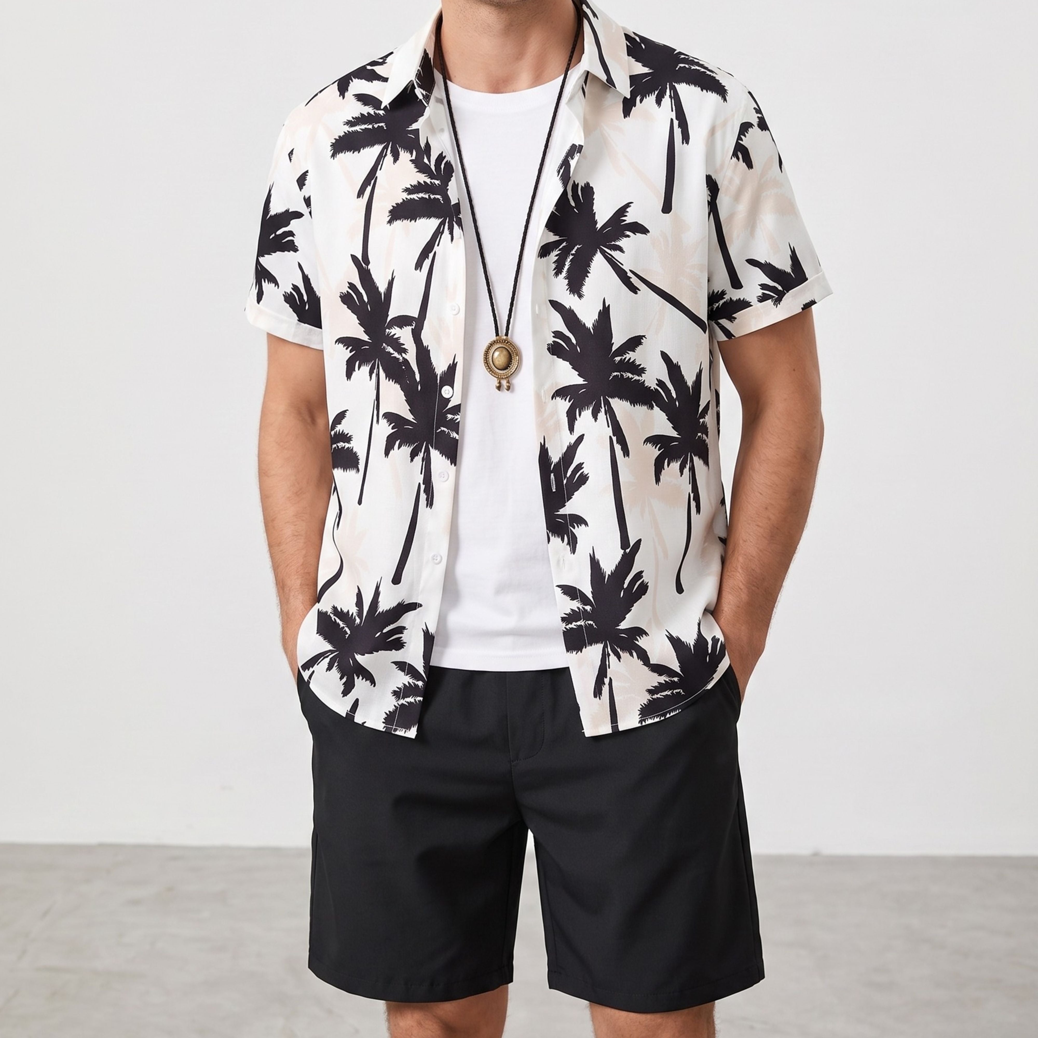 A male model posing with hands in pockets, styling the open-lapel black palm tree vacation shirt with a white undershirt and casual black pants