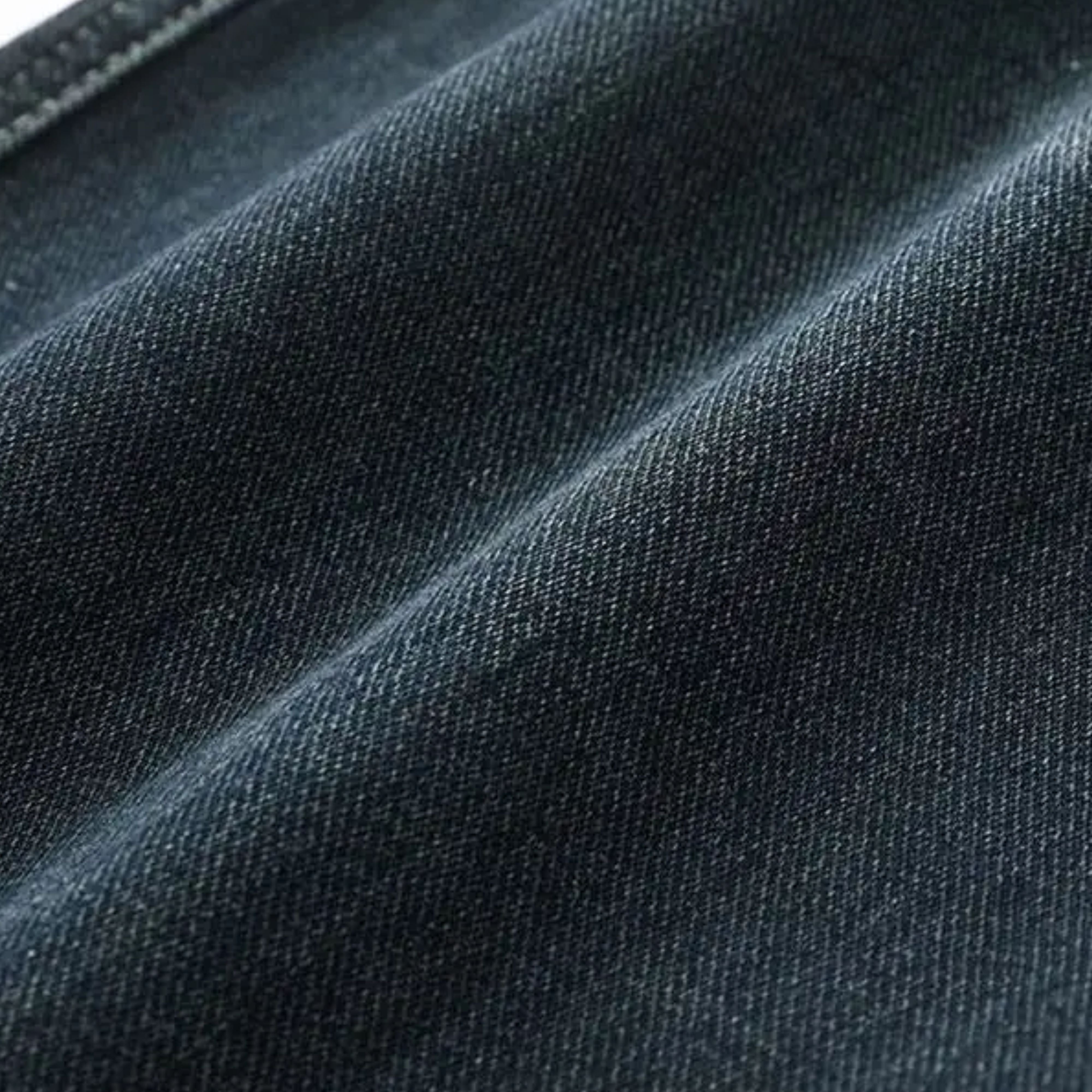 Macro close-up shot showcasing the premium snow wash texture on the dark blue midweight stretch denim fabric
