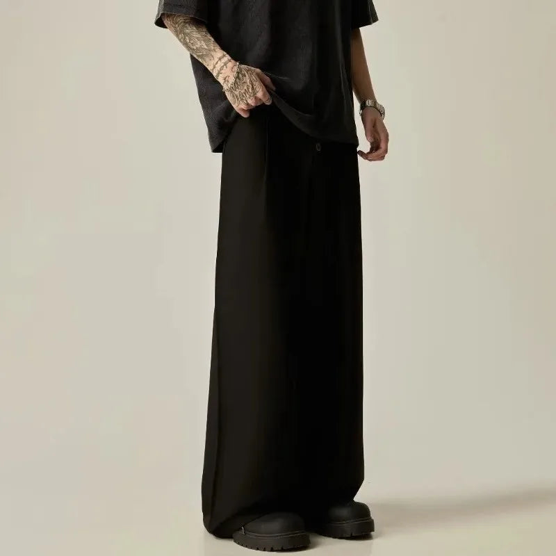Three-quarter view of a man styling loose straight wide-leg black trousers for an all-black streetwear look