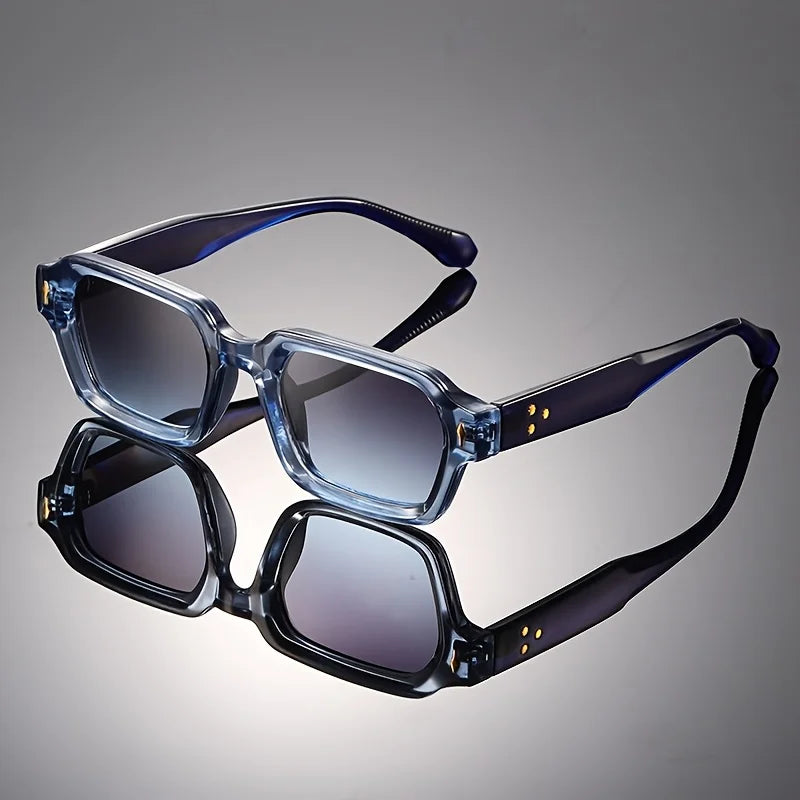 Retro chunky rectangular sunglasses with a translucent blue frame and gradient lenses reflecting on a dark studio surface.