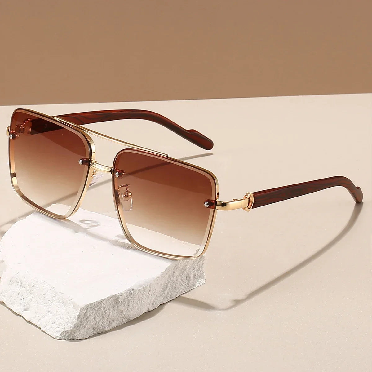 Retro square metal sunglasses with wood temples and gradient brown lenses resting on a white stone prop.