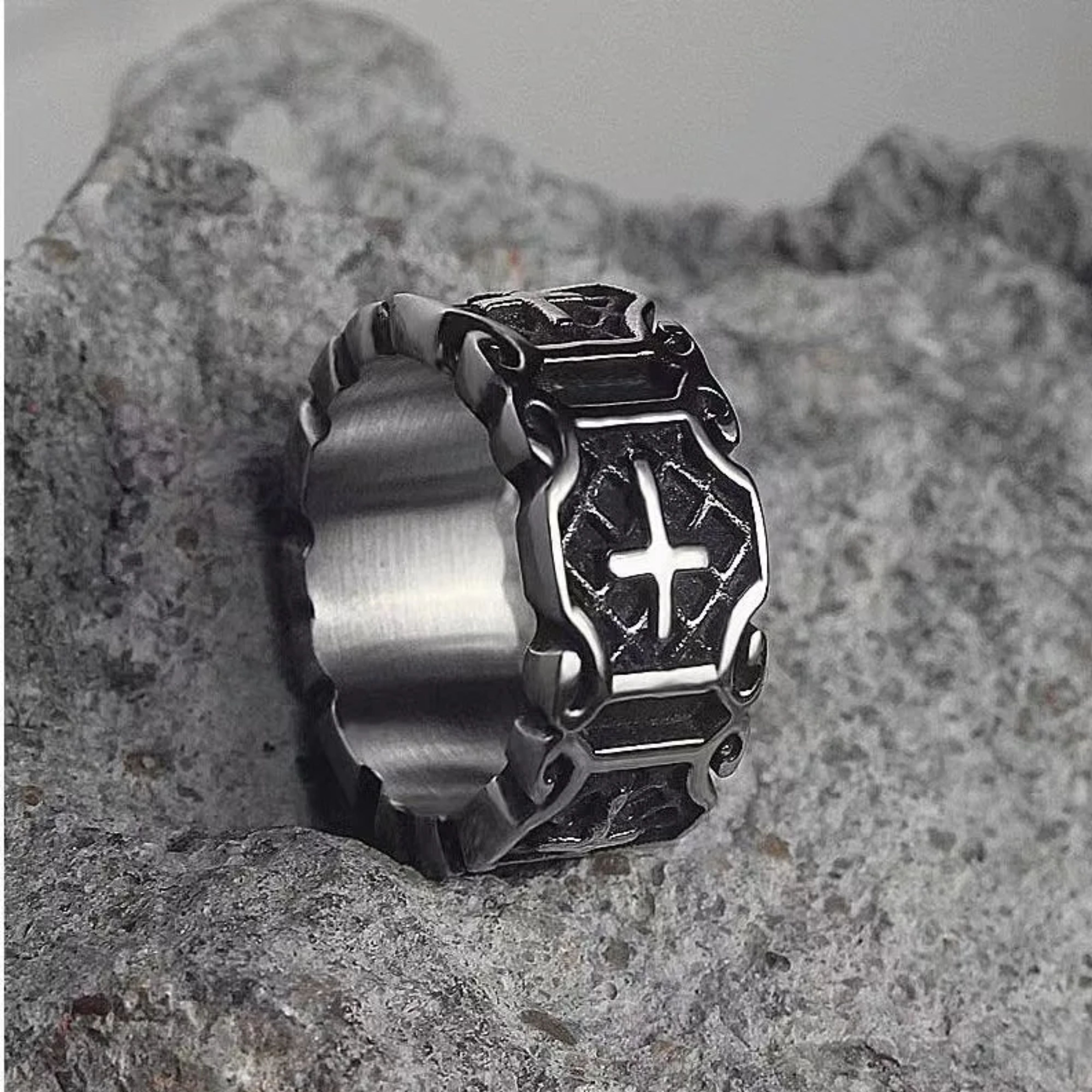 Rugged silver Templar cross ring standing upright on a textured grey rock, emphasizing its durable and masculine design.