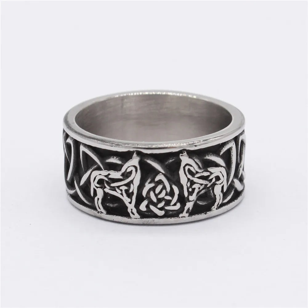 Macro shot of a silver band ring featuring two wolves facing a central Celtic knot on a white background.