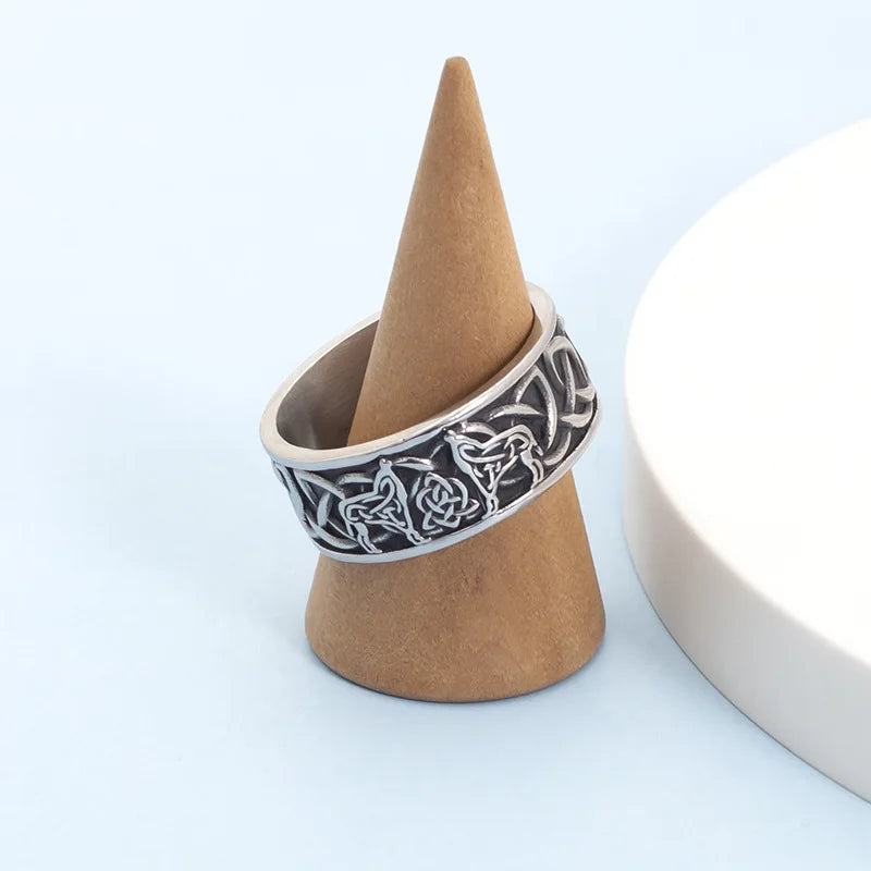 Silver Viking wolf band displayed on a small wooden ring cone stand against a light blue background.