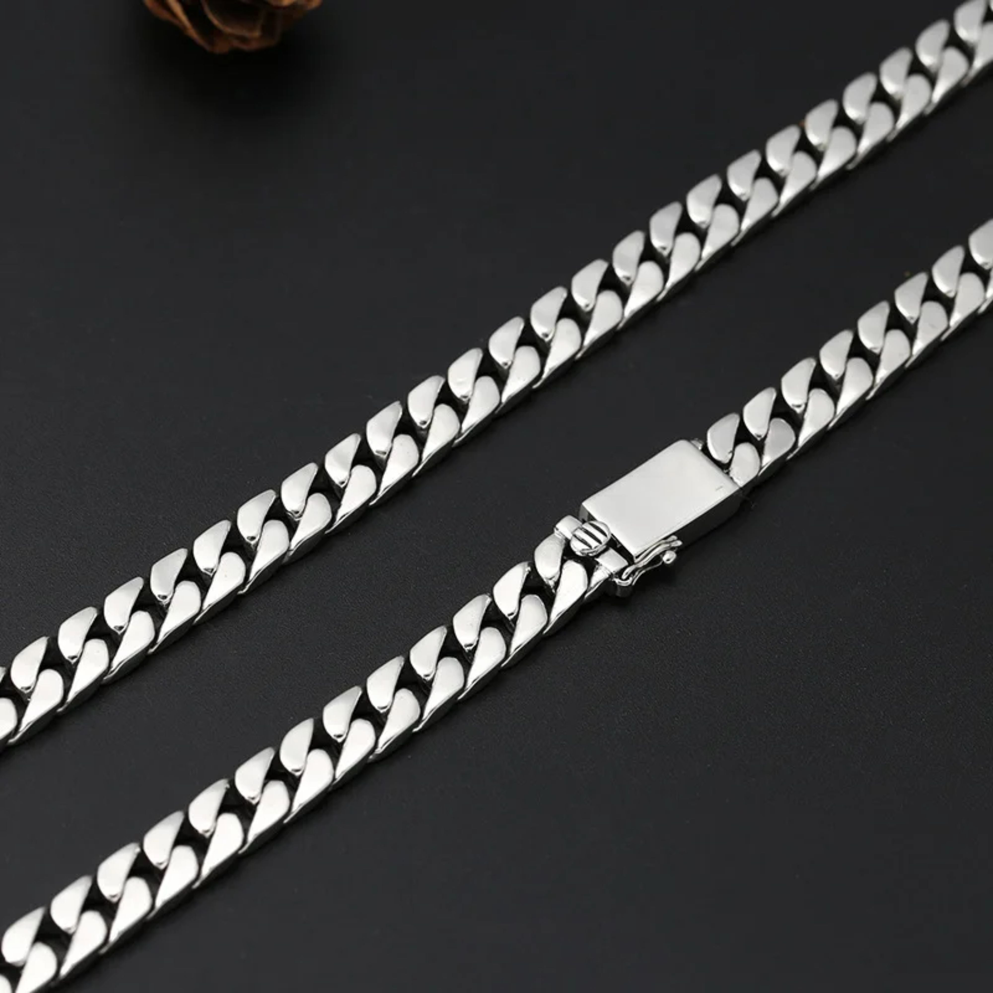 Straight length of a heavy silver Miami Cuban chain showing the sleek closed box clasp on a black background.